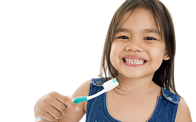 A young girl smiling with a toothbrush in her hand
