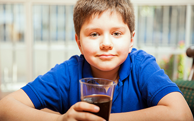 A young blonde boy drinking soda
