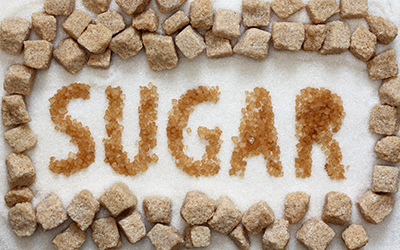 The word sugar spelled out in sugar with sugar cubes surrounding the word
