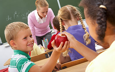 Children at school passing an apple in class