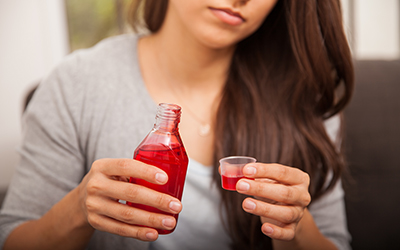 Young woman pooring cough syrup