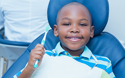 A young boy sitting in a dental chair holding a toothbrush