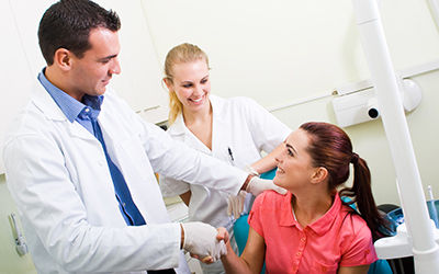 Dentist shaking hand of smiling patient