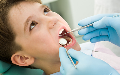 A young boy having his teeth looked at