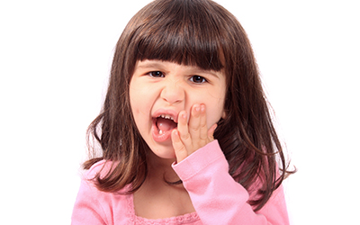 A young girl holding her mouth in pain